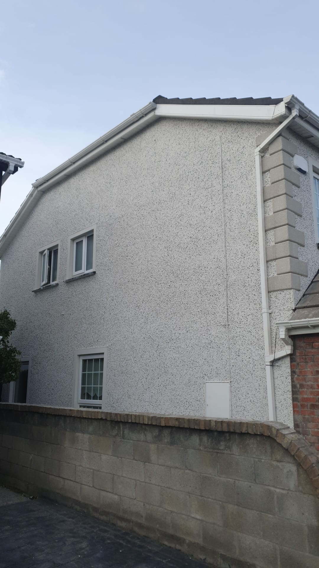 A white house with a brick wall and a blue sky in the background.