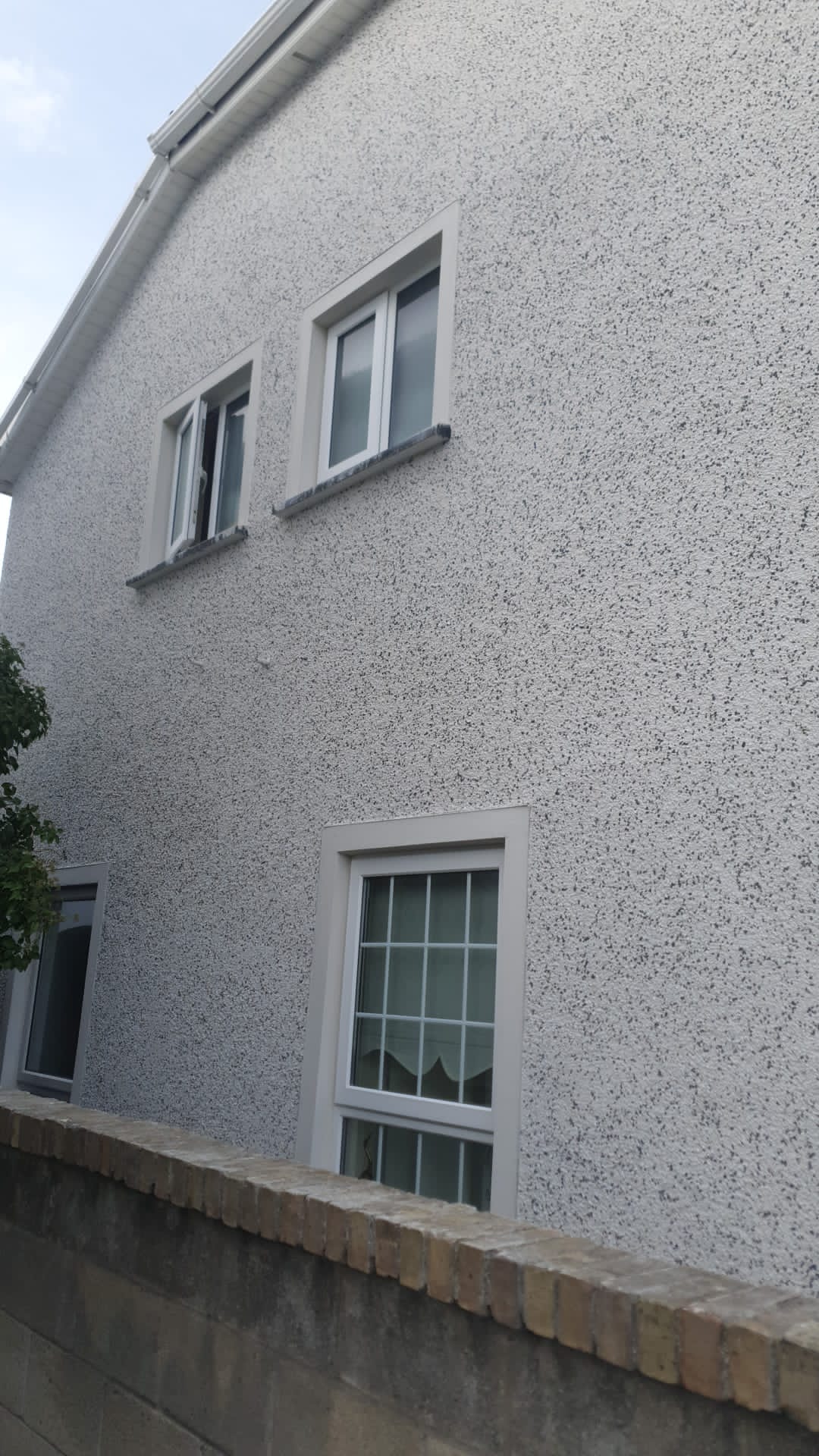 A large white house with a lot of windows and a brick wall.