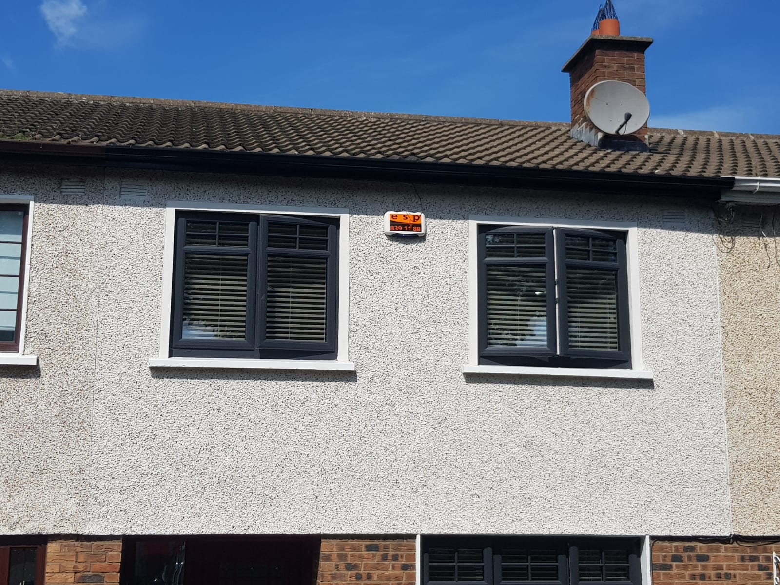 A house with two windows and a satellite dish on the roof.