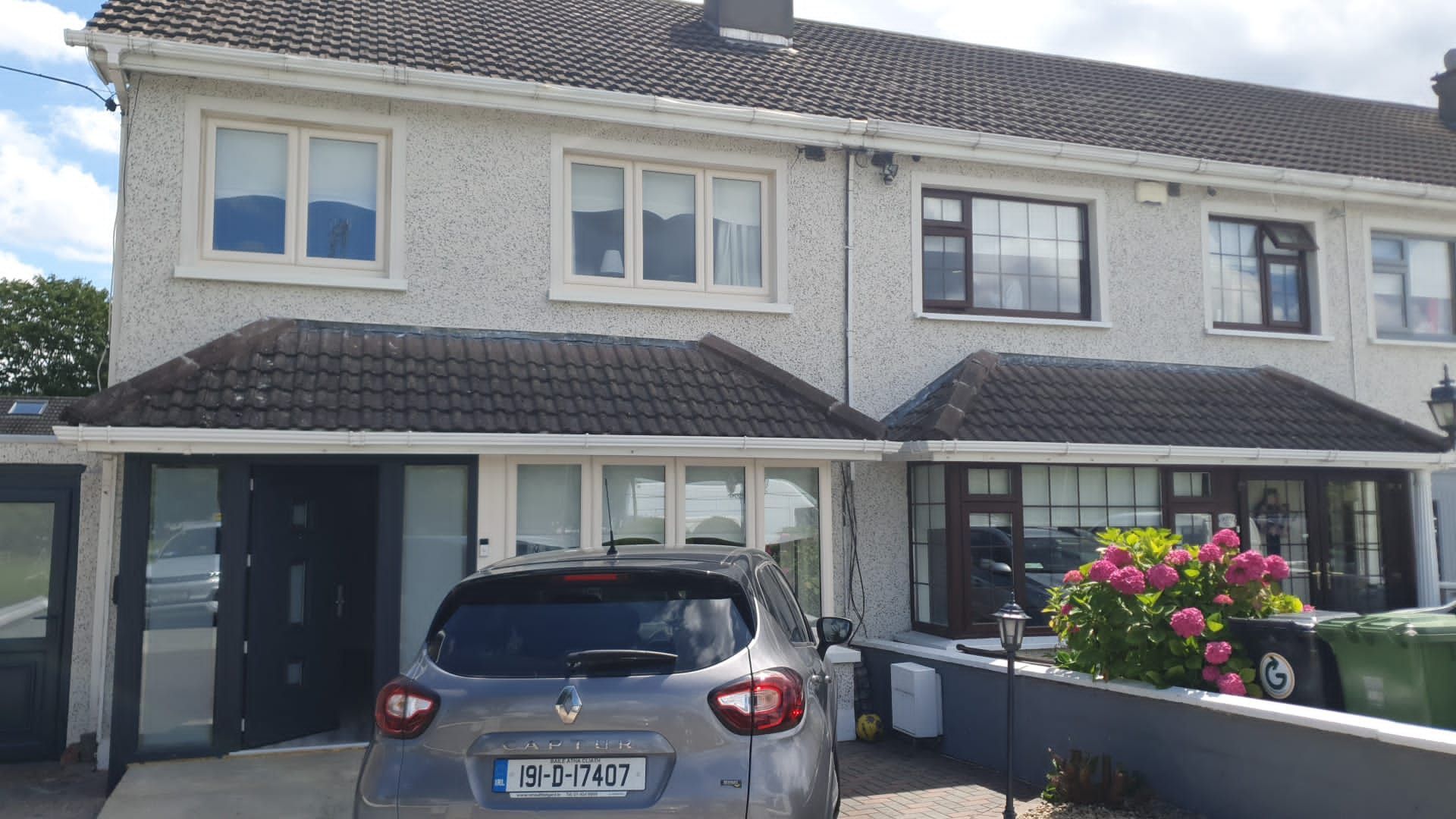 A car is parked in front of a white house.