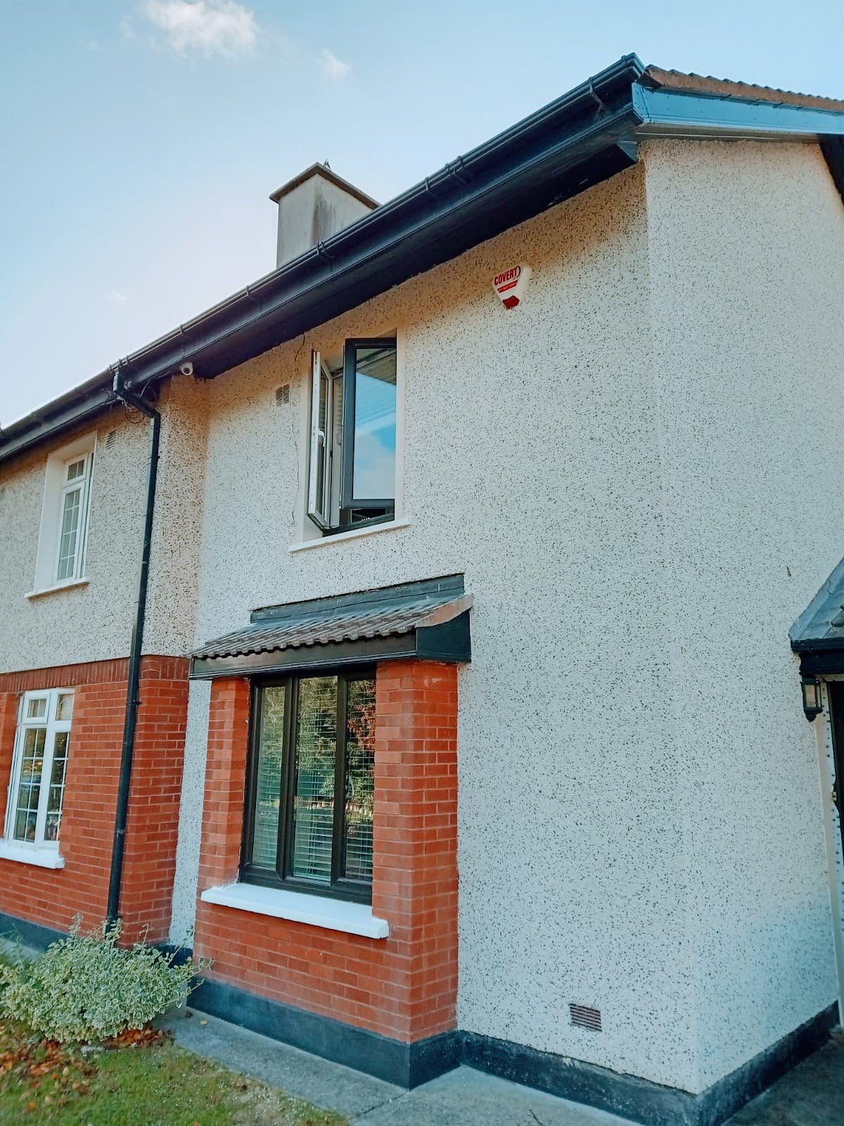 A white house with red bricks and a black roof