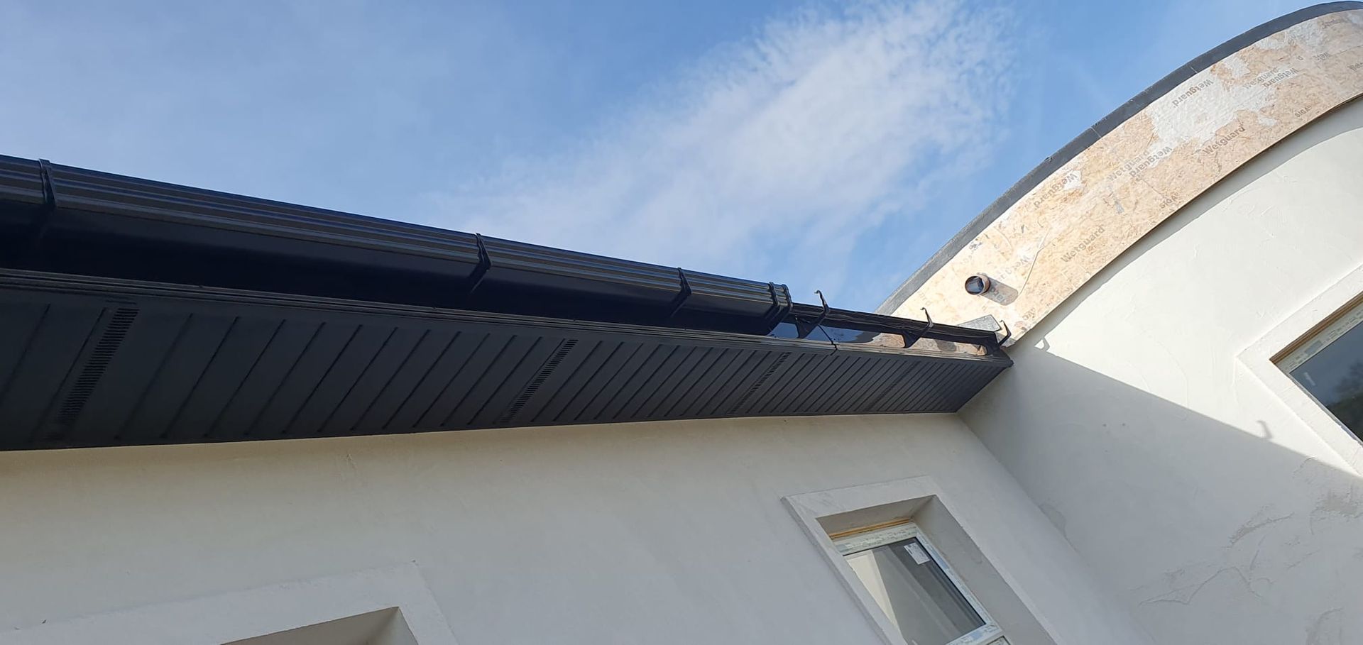 Looking up at the roof of a building with a blue sky in the background.