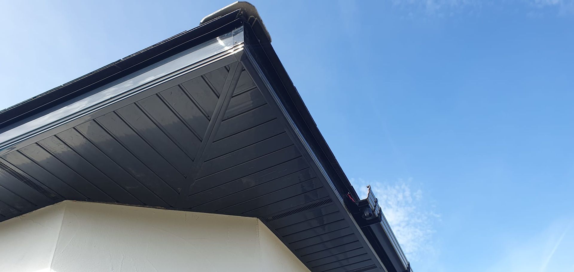 A close up of the roof of a house with a blue sky in the background.