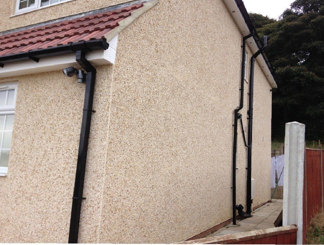 The side of a house with black pipes on it
