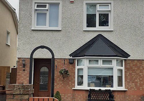 The front of a house with two windows and a porch.