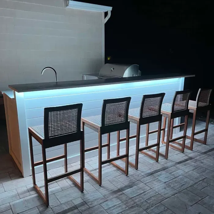 A row of bar stools are lined up in front of a counter.