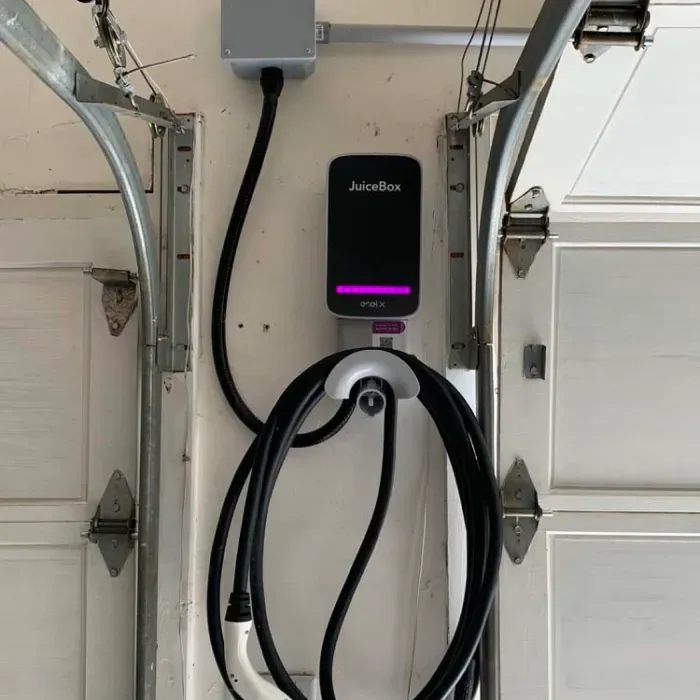 An electric car charger is attached to the side of a garage door