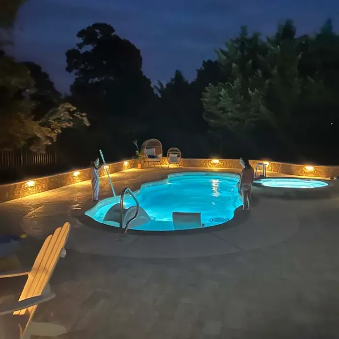 A large swimming pool is lit up at night.