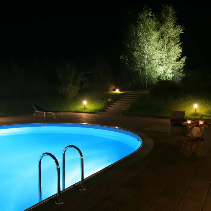 A swimming pool is lit up at night with stairs leading to it
