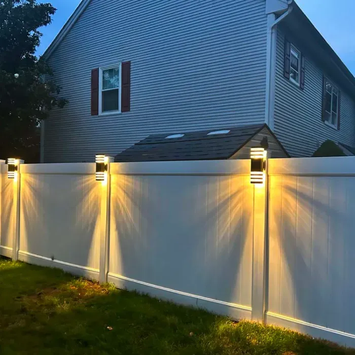A white fence with lights on it in front of a house