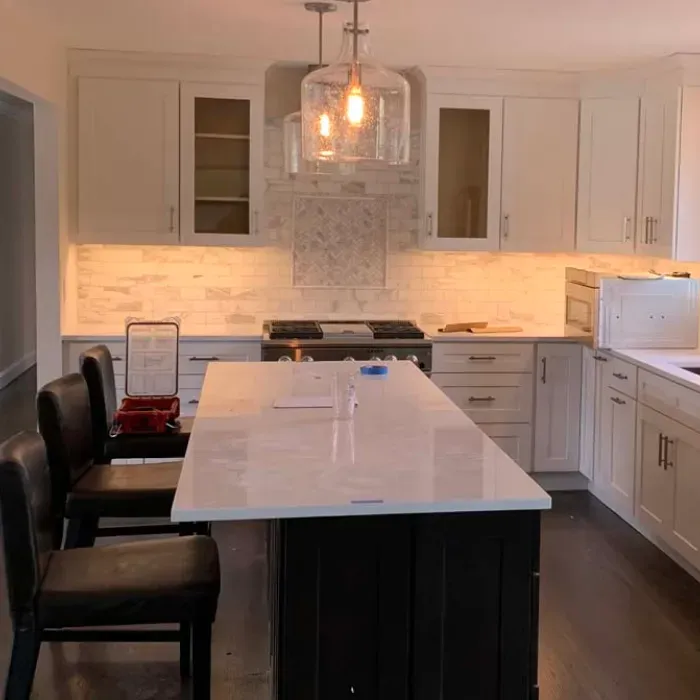 A kitchen with white cabinets and a large island in the middle.