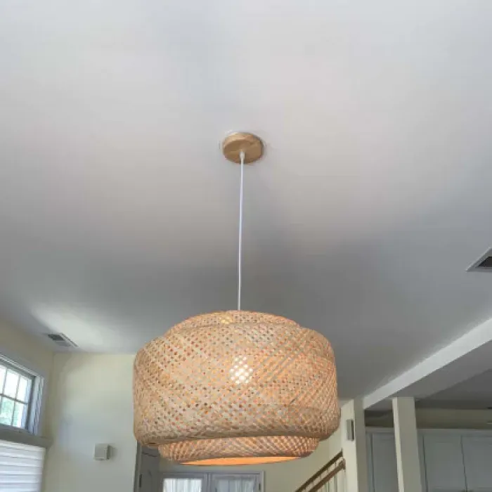A wicker pendant light is hanging from the ceiling in a living room.
