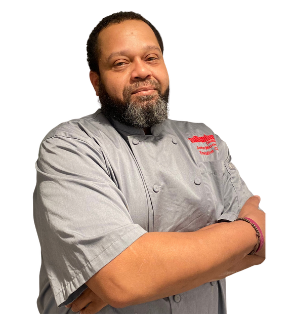 Chef in gray uniform with crossed arms, logo on shirt, looking at the camera.