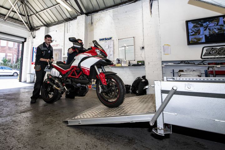 mechanics putting motorbike in trailer