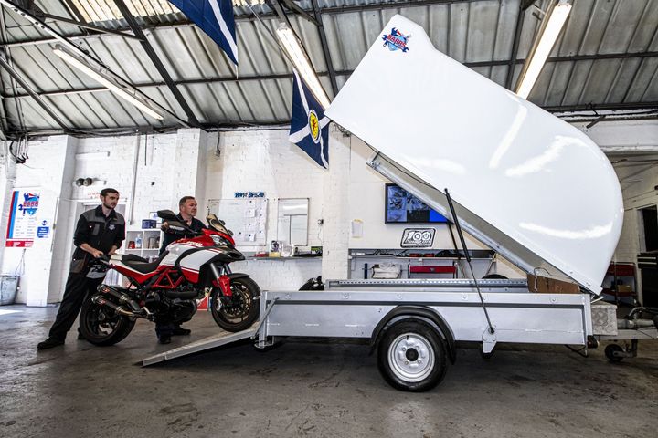 mechanics putting motorcycle in trailer