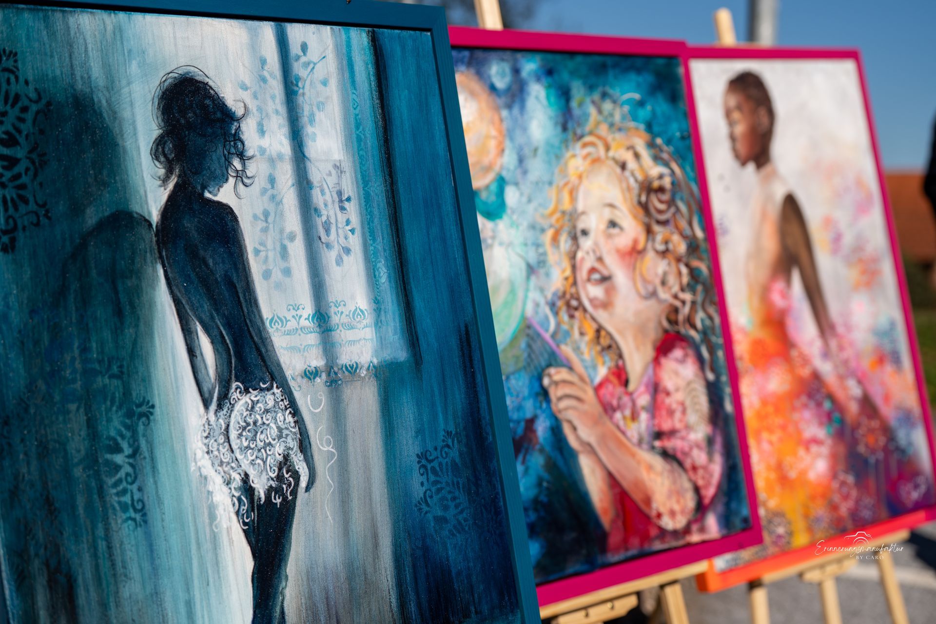 Im Freien ausgestellte Kunstwerke: Silhouette, Kinderporträt, Frau im Kleid.