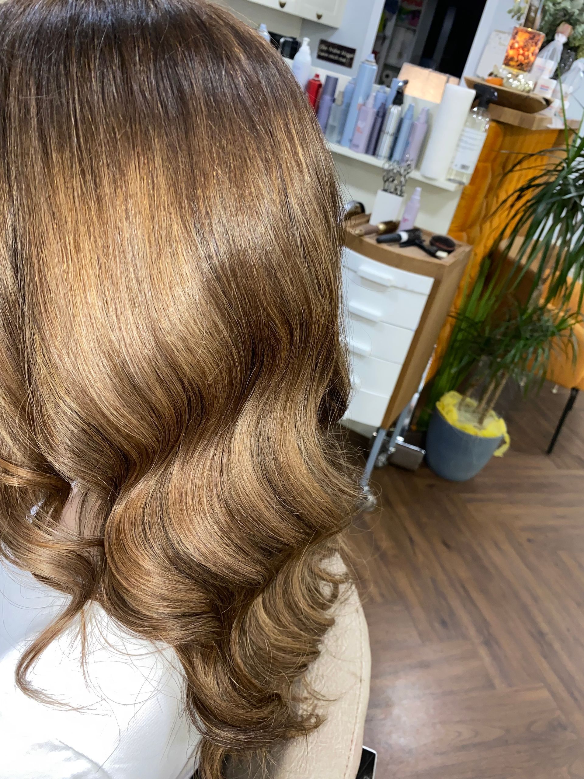 Nahaufnahme von gestyltem, hellbraunem Haar mit großen, lockigen Wellen.