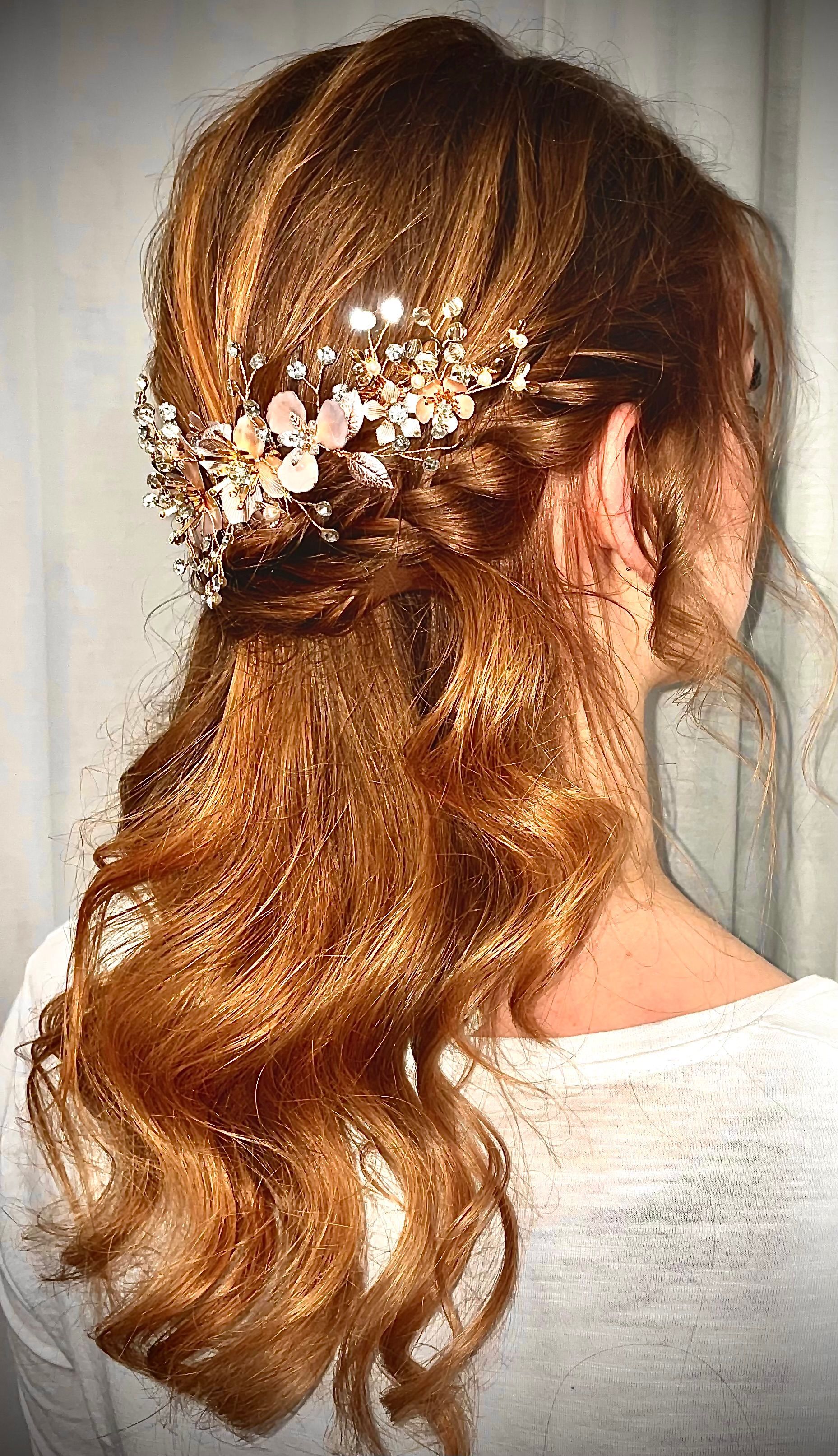 Frau mit gewelltem, rötlich-braunem Haar, das mit einem kunstvollen Kopfschmuck frisiert ist; halb hochgesteckte Frisur.