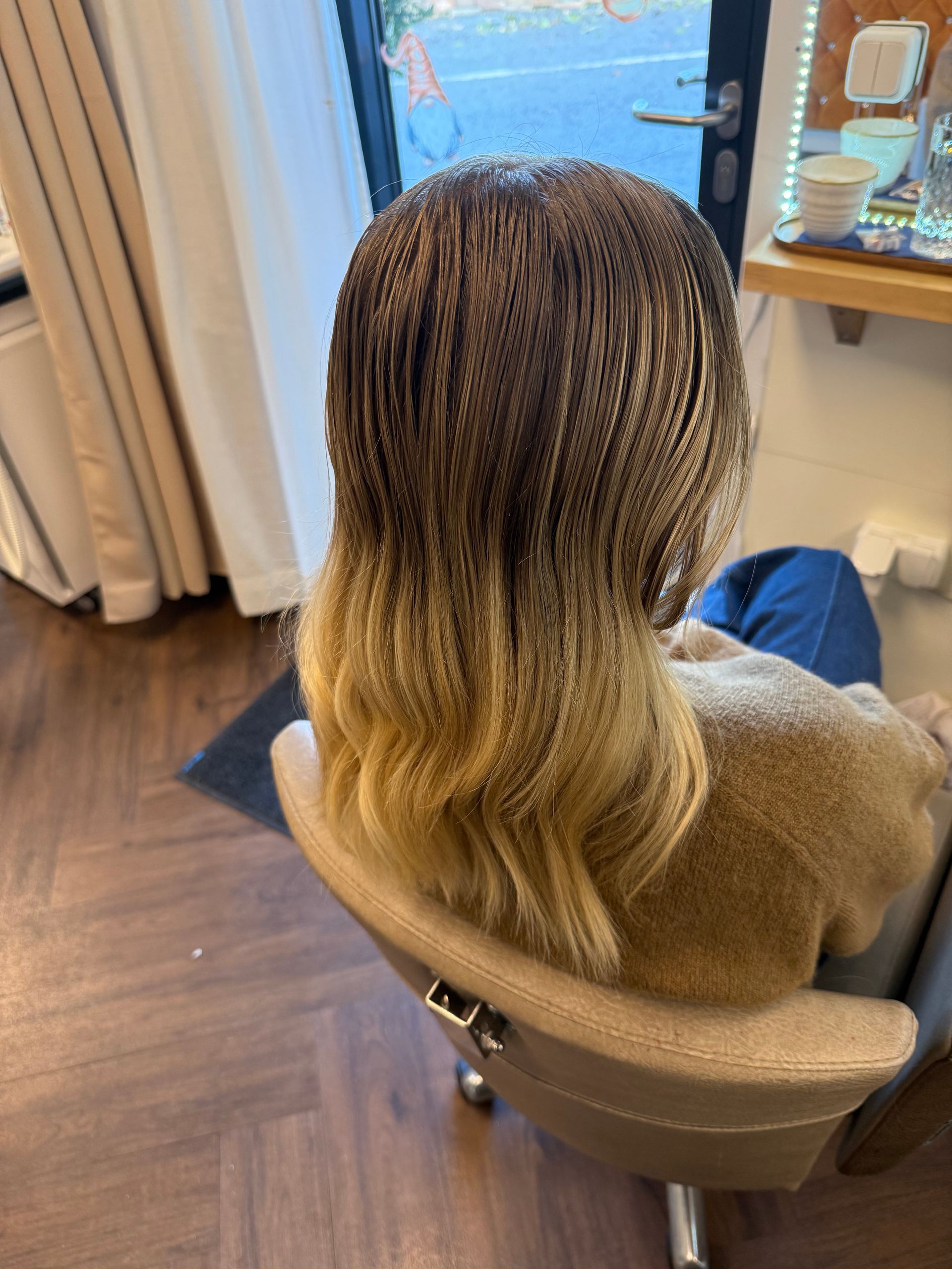 Eine Person mit langen, hellbraunen Haaren in einem Friseursalon.