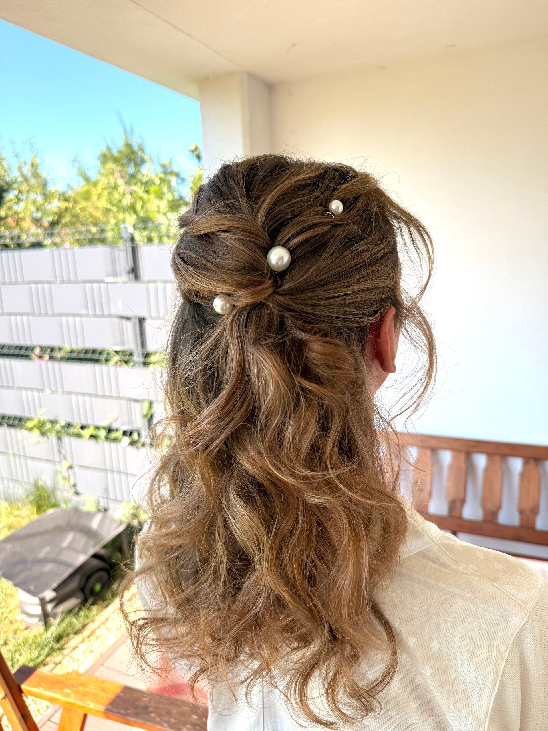 Die roten Haare der Frau sind zu einem Dutt hochgesteckt, der mit einer Perlenhaarspange befestigt ist.