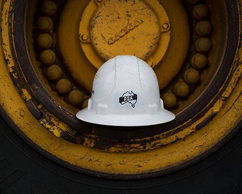A white hard hat is sitting on top of a yellow wheel.