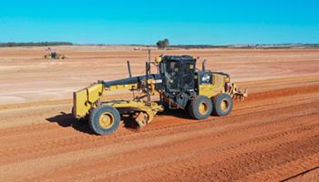 An aerial view of a bulldozer moving dirt in a field.