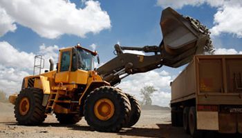 A bulldozer is loading a dump truck with dirt.