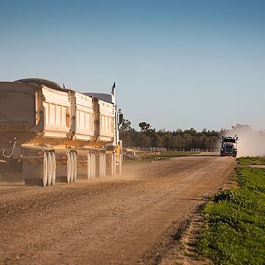 A dump truck is driving down a dirt road.