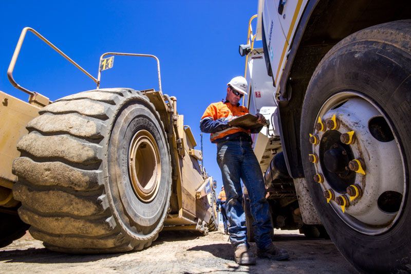 A man is standing next to a truck and looking at a clipboard.