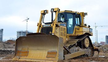 A bulldozer is sitting in the dirt on a construction site.