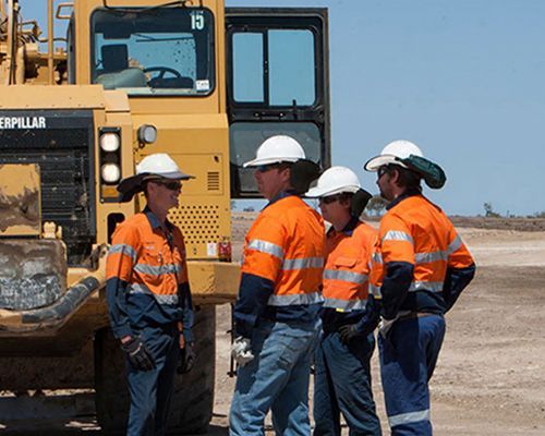 A group of construction workers are standing in front of a caterpillar truck