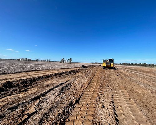 A yellow bulldozer is driving down a dirt road.