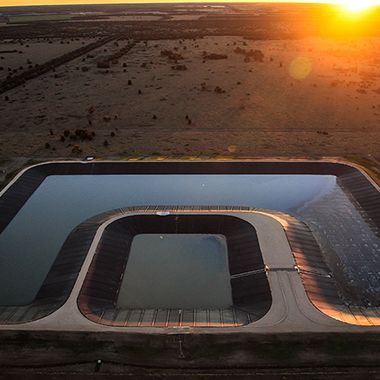 An aerial view of a large body of water in the middle of a desert at sunset.