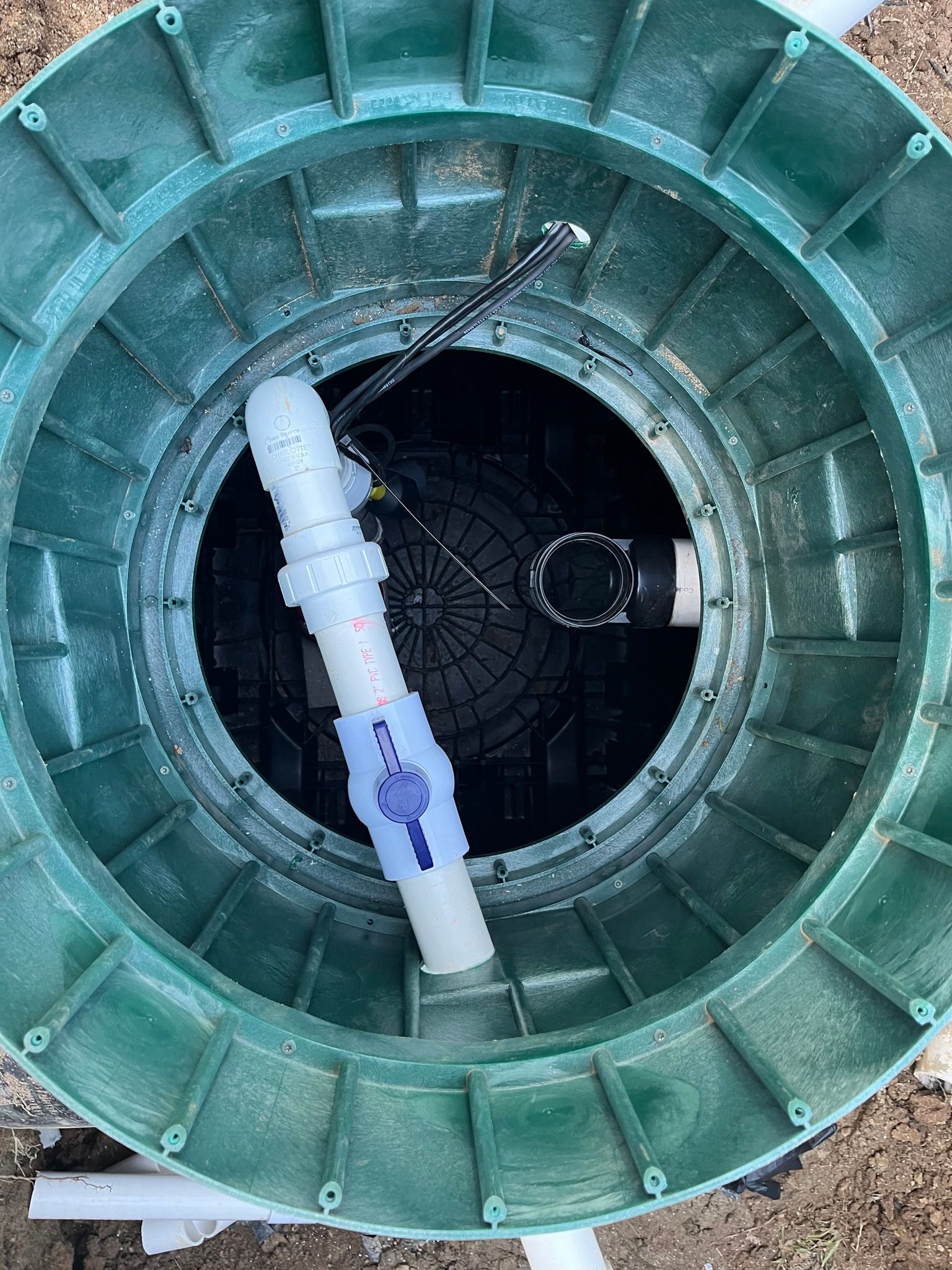 Green septic tank with open lid, showing interior plumbing and components.