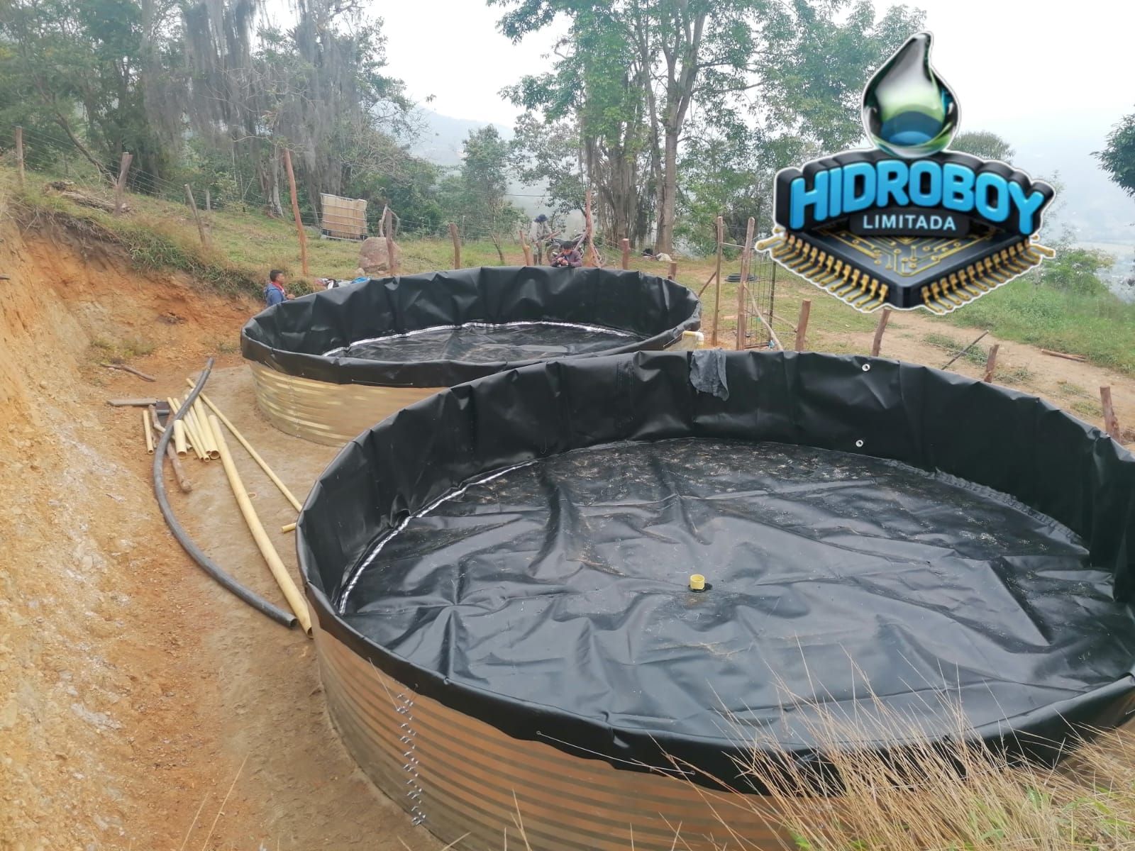 Canal de riego revestido con agua estancada junto a tierras de cultivo cubiertas de hierba