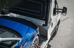 A blue car is being towed by a tow truck.