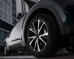 A close up of a car wheel with a building in the background.