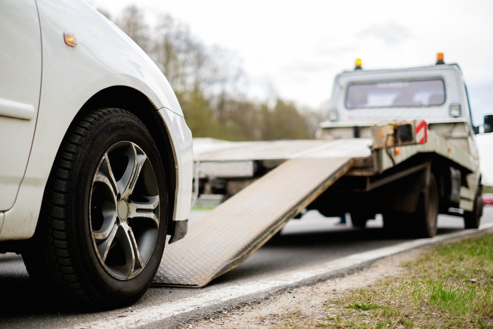 A car is being towed by a tow truck on the side of the road.