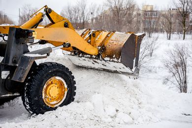Yellow snowplow clearing snow. Winter scene.