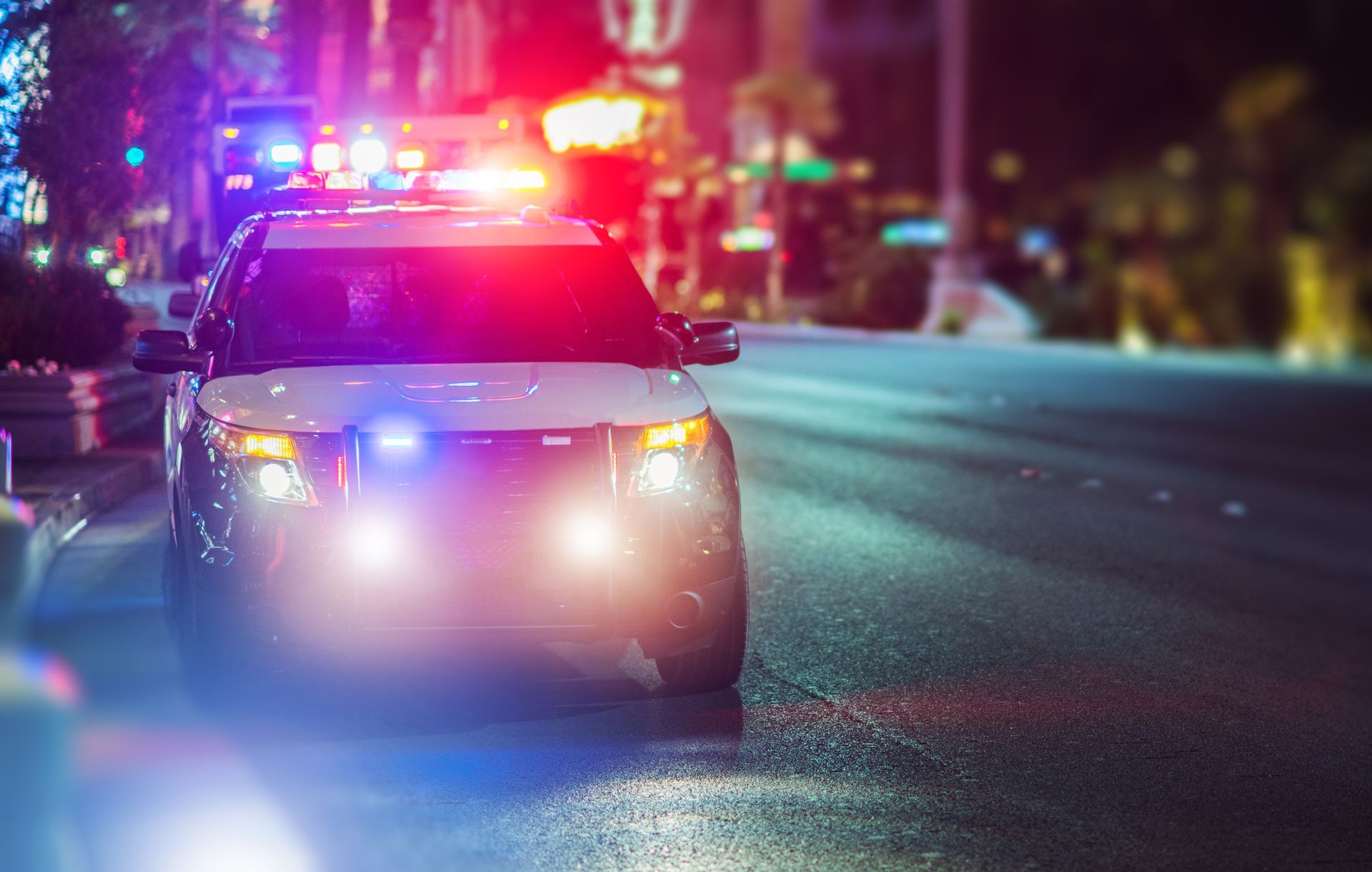 Police car with flashing red and blue lights at night.