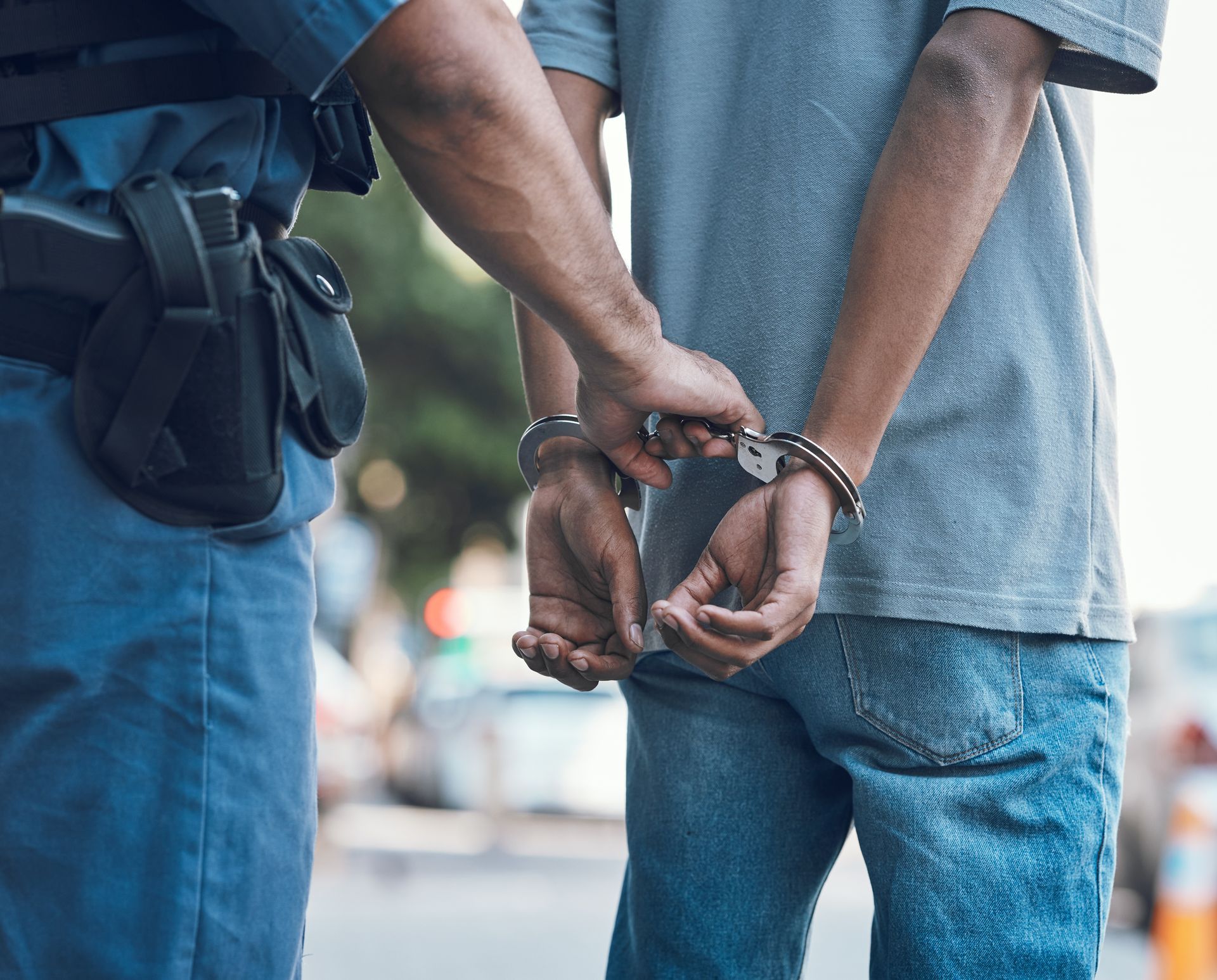 A police officer handcuffs a man's wrists outdoors.