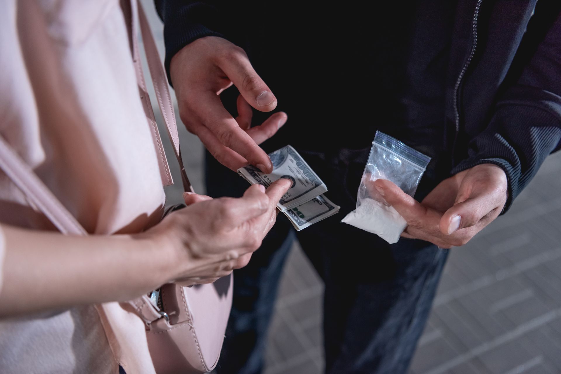 Person exchanging money for a bag of white powder, potentially drugs.