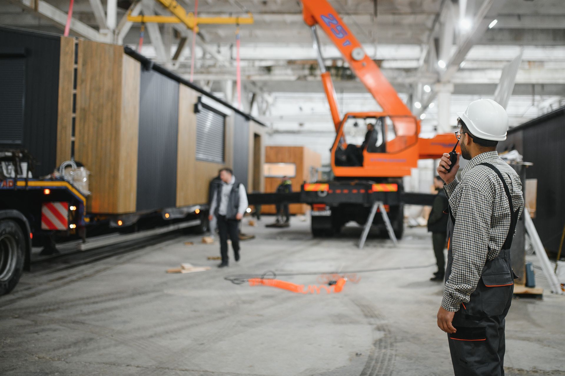 Warehouse worker in orange hard hat operating a pallet jack, moving a cardboard box, from an overhead view.
