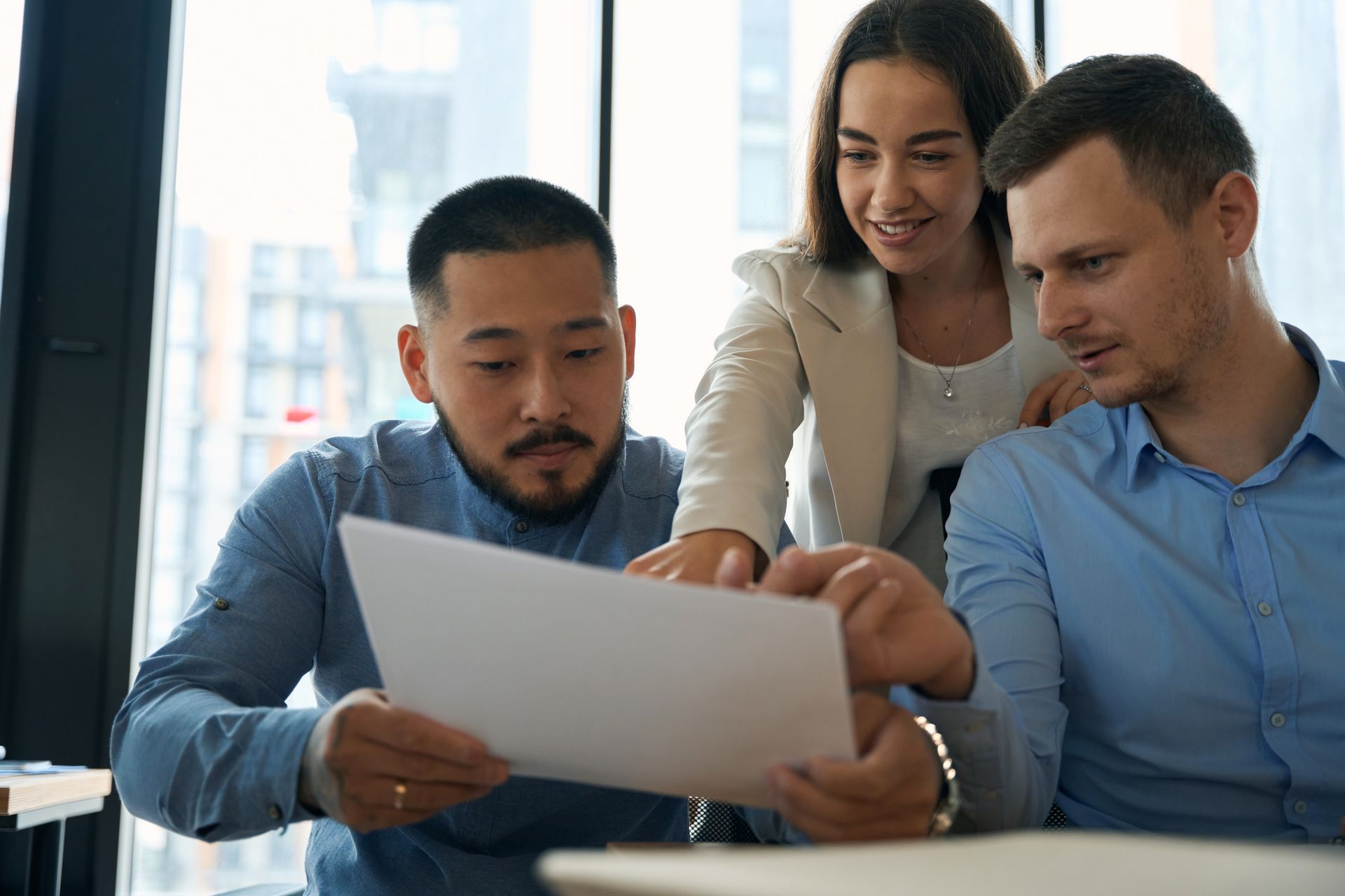 Three colleagues looking at document in a bright office.