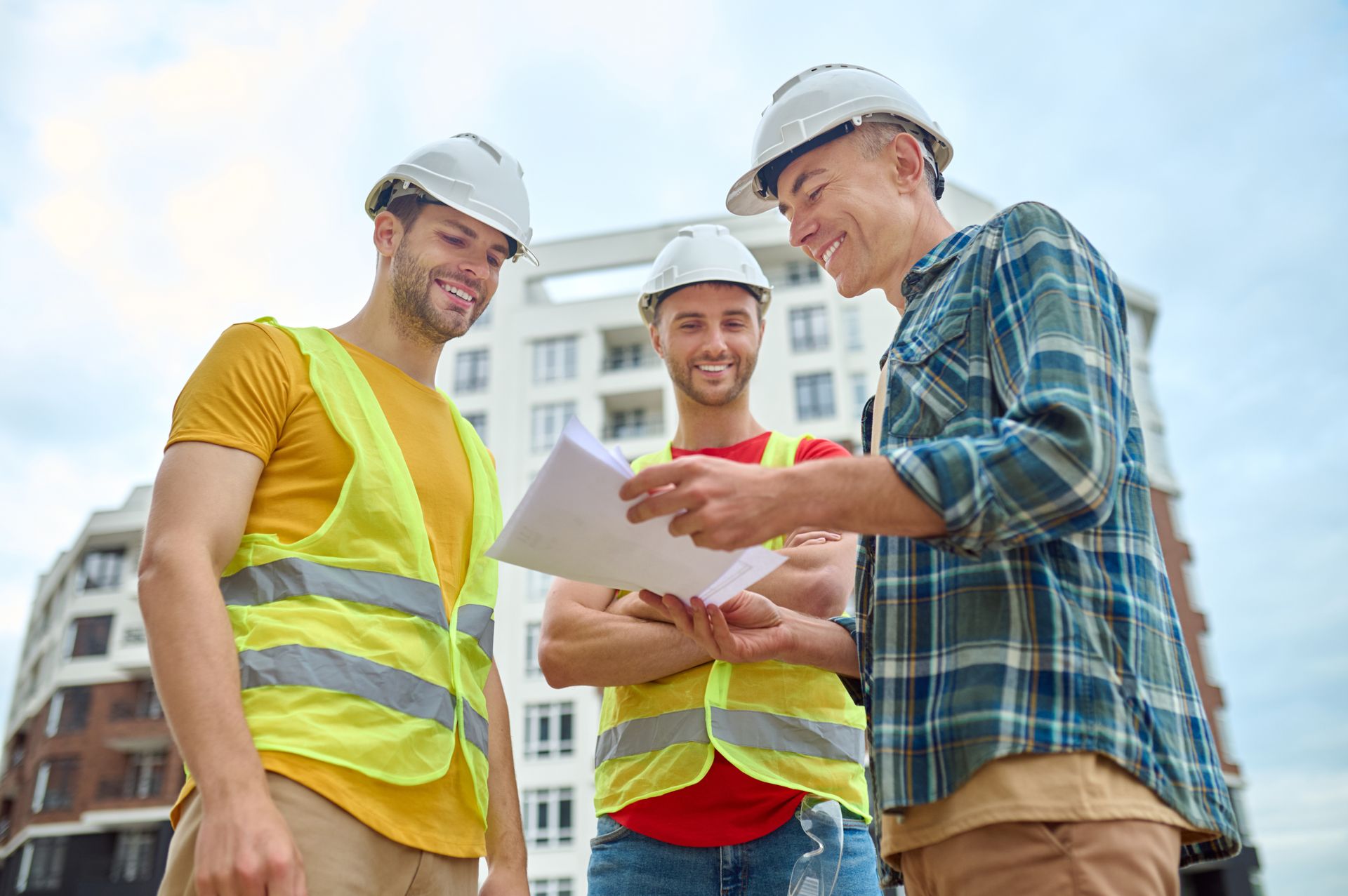 Construction workers in hard hats reviewing documents on a building site.
