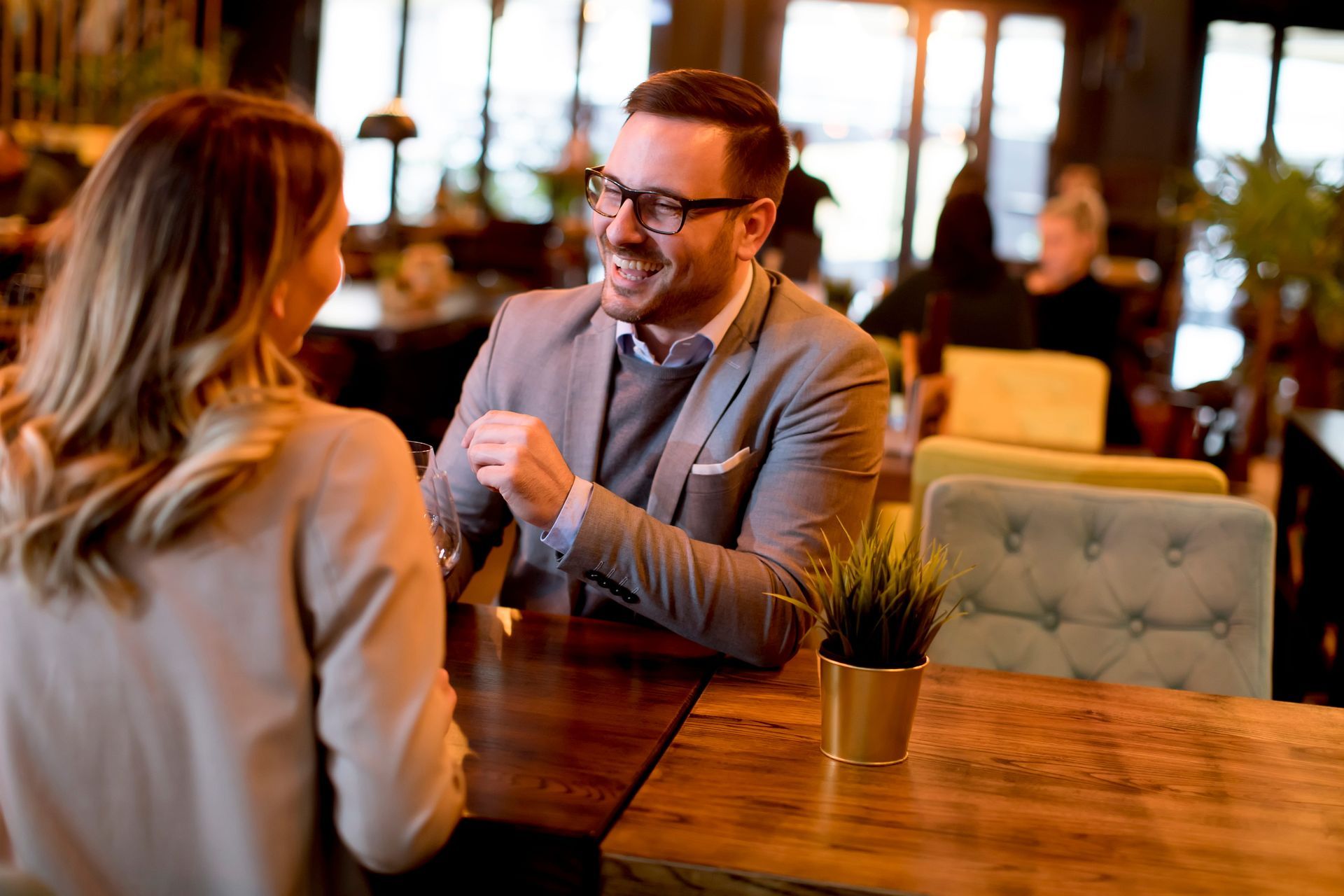 A man and woman smiling at each other while seated at a table in a restaurant.