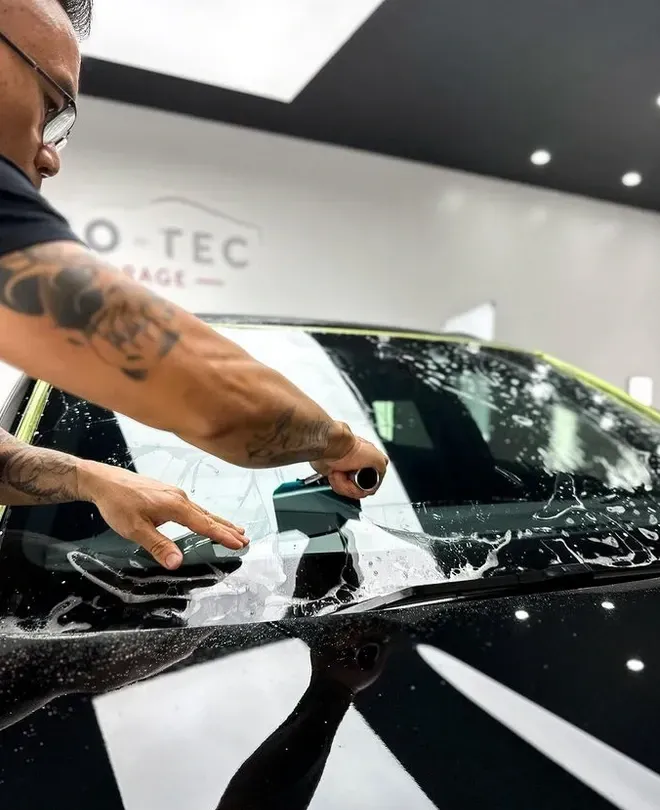 installing windshield protection film of a car in a garage.