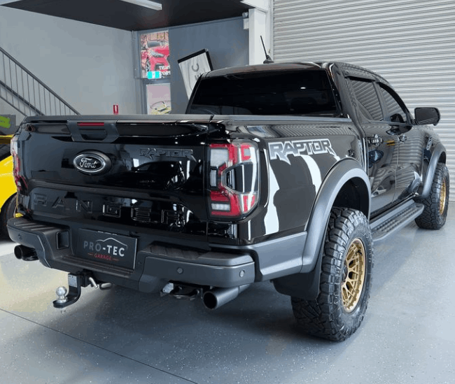 A black raptor truck is parked in a garage with ceramic coating