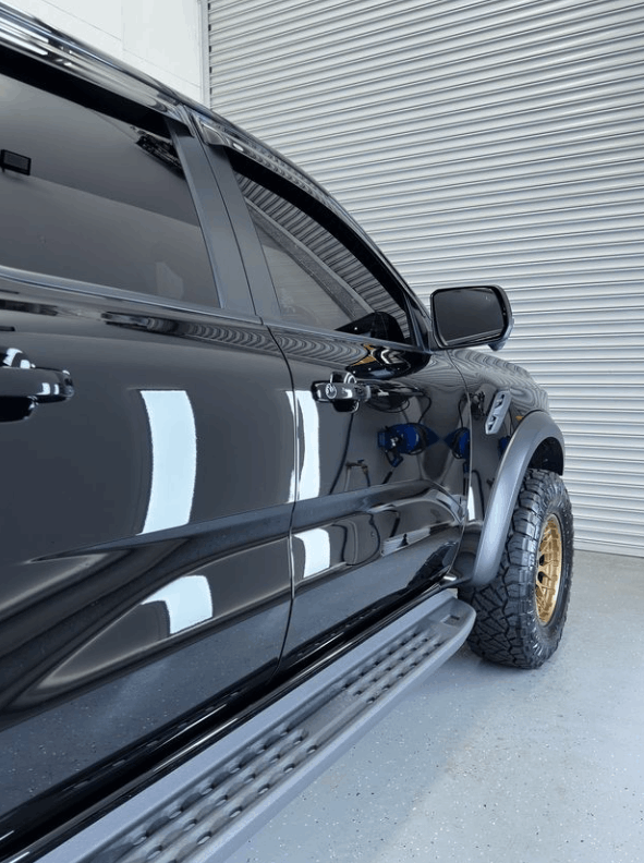 A black truck is parked in front of a garage door with ceramic coating