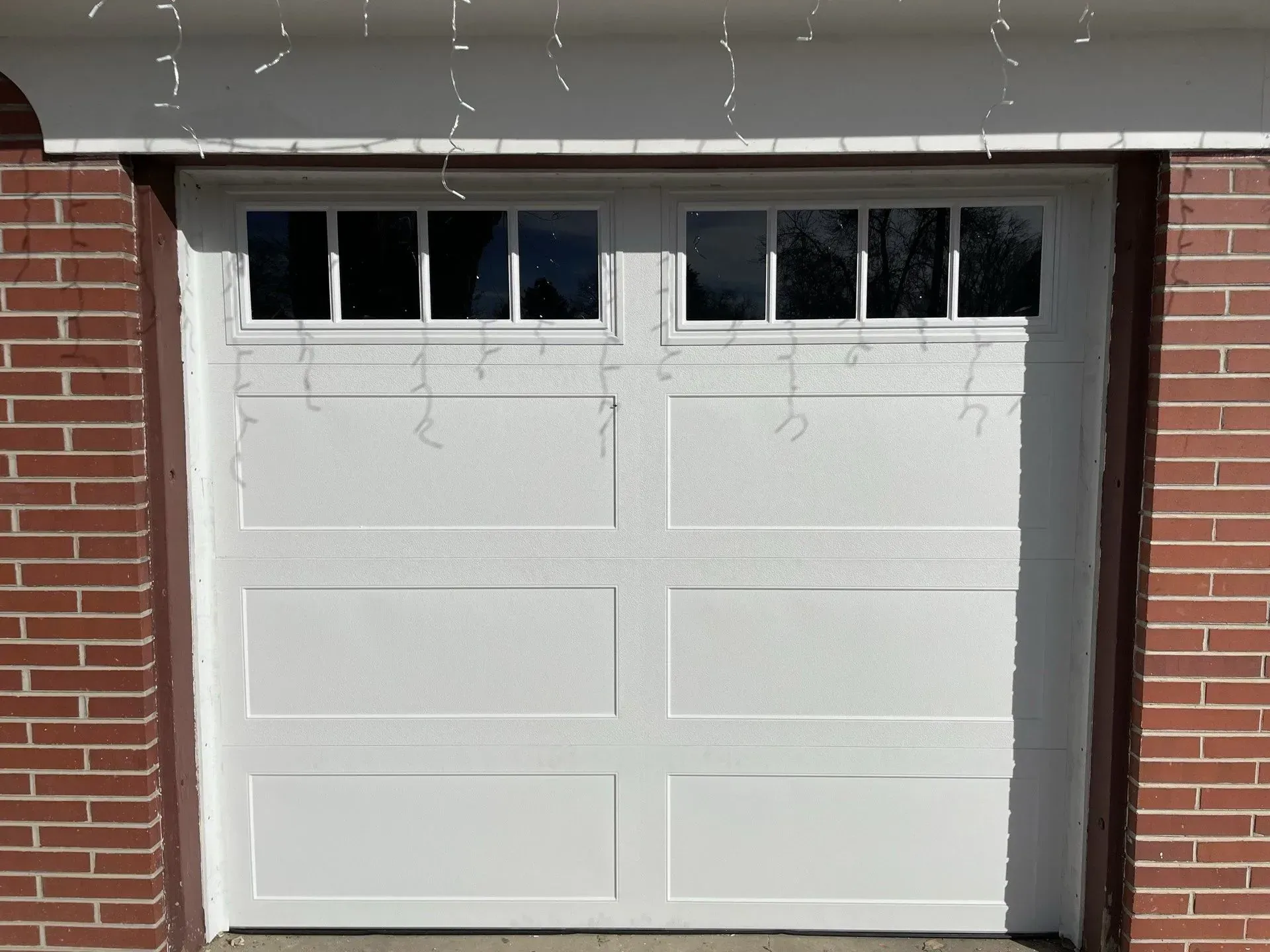 White garage door with small windows on a brick house exterior
